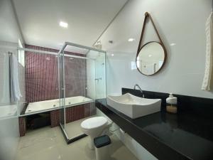 a bathroom with a sink and a toilet and a mirror at Requinte e Conforto na Praia do Morro in Guarapari +47 photos