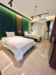 a bedroom with two beds and a green wall at Duplex villa in Beverly Hills in Sheikh Zayed