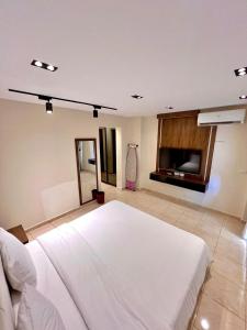 a bedroom with a large white bed and a tv at Duplex villa in Beverly Hills in Sheikh Zayed