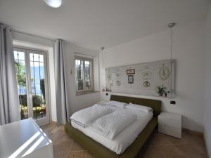 a bedroom with a large bed with white sheets at Villa with Panoramic Views for 6 in Oggebbio
