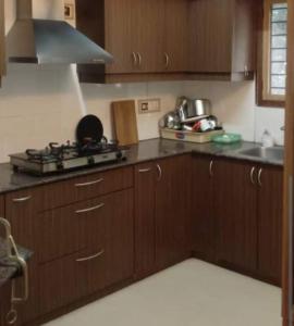 a kitchen with wooden cabinets and a stove top oven at Puthooram Veedu in Kannur