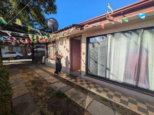 a woman standing outside of a house at Hostel INK - Duerme Como En Casa in Concepción