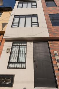 a building with a black door and windows at Denier House Fuente de los Rosales - A 5 minutos de Centros Comerciales in Ibagué