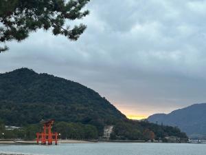 a red object in the water with a mountain at 桜庵 sakura an in Hatsukaichi