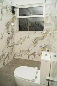 a bathroom with a white toilet and a marble wall at Trinco Beachfront Villas AJS in Trincomalee +69 photos