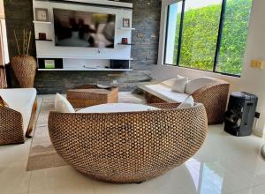 a living room with wicker chairs and a tv at Espectacular Casa Quinta in Girardot
