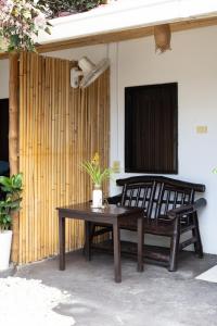 a bench and a table in front of a house at Trisha Guesthouse in San Vicente
