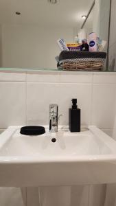 a white bathroom sink with a soap dispenser on it at Urban Retreat - Leeds City Centre - Sleeps 4 in Central Station