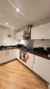 a kitchen with white cabinets and a wooden floor at Urban Retreat - Leeds City Centre - Sleeps 4 in Central Station