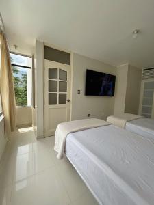 a bedroom with two beds and a tv on the wall at Alojamiento Jaén in Jaén