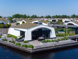 a large white house with a roof next to the water at Aquaronde 122 in Lemmer