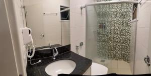 a bathroom with a sink and a shower with a phone at Apto Mais Decor in Salinas