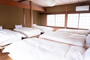 a room with four white beds in it at Kaitan雲津 in Matsue