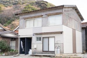 a white house with a mountain in the background at Kaitan雲津 in Matsue