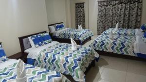 a bedroom with three beds with blue and white sheets at Refugio Volcán Tungurahua in Ambato
