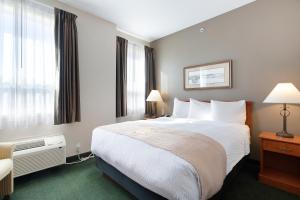 a hotel room with a large bed and windows at Lakeview Inns & Suites - Okotoks in Okotoks