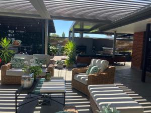 a patio with couches and chairs and a table at Maples on Harewood in Christchurch