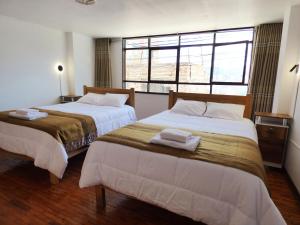 two beds in a room with a window at Tierra Espiritual - Andean Holistic Hotel in Puno