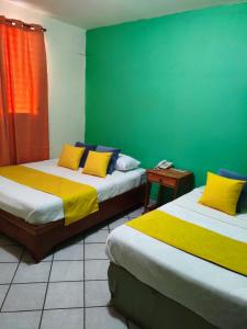 two beds in a room with a green wall at Hotel Los Rivera in David