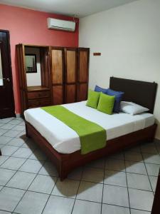 a bedroom with a large bed with green and blue pillows at Hotel Los Rivera in David
