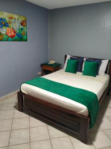 a bedroom with a large bed with green pillows at Hotel Los Rivera in David