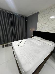 a bedroom with a large bed with white sheets at Studio 94 in Parauapebas