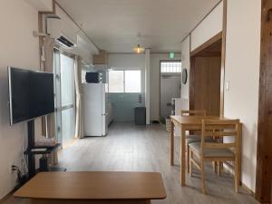 a living room with a dining room table and a television at House 1956 in Itoman