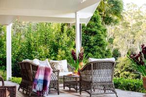 an outdoor patio with wicker chairs and an umbrella at Nightcap Ridge - Byron Bay Hinterland in Dorroughby +79 photos