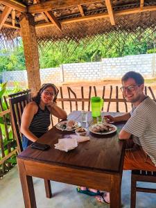 a man and woman sitting at a wooden table with food at Cormorant Bath in Netolpitiya +31 photos
