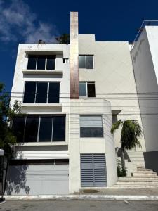 a white building with a tree in front of it at Balam Suites in Playa del Carmen