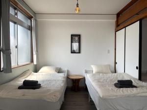 a room with two beds and a table and two windows at House 1956 in Itoman