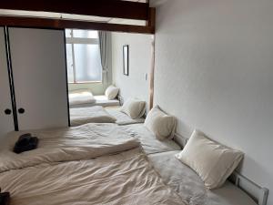 a room with four beds with white sheets and a window at House 1956 in Itoman