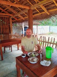 a man sitting at a table with a plate of food at Cormorant Bath in Netolpitiya