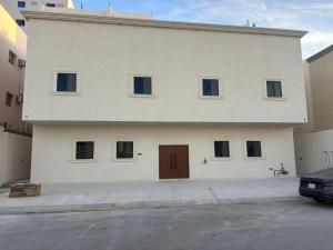 a large white building with a brown door on it at ZA apartment in Al Ahsa