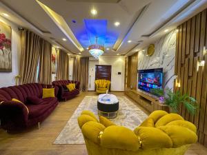 a living room with yellow furniture and a flat screen tv at Engeemos Bookastay Apartments in Abeokuta