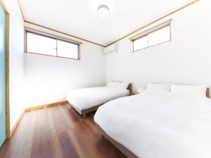 a bedroom with two beds and two windows at マーケットステイ串本 MarketStay Kusimoto in Kushimoto