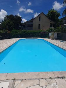 a blue swimming pool in front of a house at Duplex cosy avec piscine à 2mn de la plage - Kaz Ti Plaj in Les Trois-Îlets