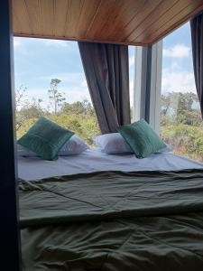 a bed in a room with a large window at The Fortunara Crown Munnar in Munnar