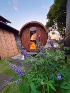 a small wooden house in a garden with purple flowers at いとしま風遊 in Itoshima