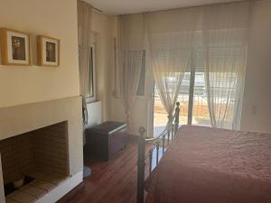 a bedroom with a bed and a fireplace and a window at Lagonisi Beach Villa in Lagonissi