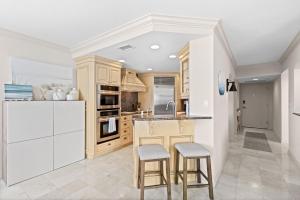 a kitchen with white cabinets and a counter with stools at Privateer #601 in Longboat Key