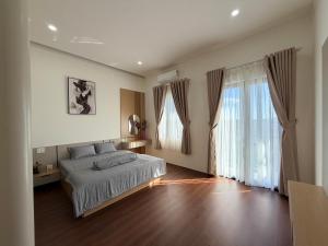 a bedroom with a bed and a large window at Lúa Vàng homestay in Pleiku Airport