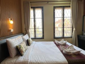 a bedroom with a large bed with two windows at Mixay Paradise Hotel in Vientiane +45 photos