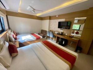 a hotel room with two beds and a desk at Hotel Royal Bengal in Bolpur