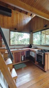 a kitchen with wooden cabinets and a staircase in a cabin at Floresta Mandaçaia in São Roque