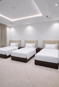 two beds in a room with white walls at O2P Al Salam in Medina