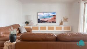 a living room with a brown couch and a television on a wall at Summerland Escape in Summerland Point