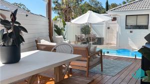 a patio with a table and chairs and a pool at Summerland Escape in Summerland Point