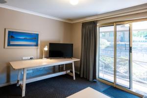 a room with a desk with a tv and a window at Grandis 35 in Albany