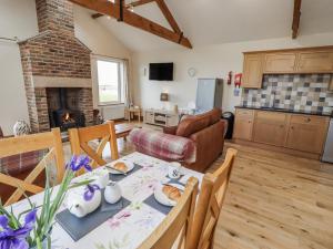 a kitchen and living room with a table and a couch at Home Stead Cottage in Embleton